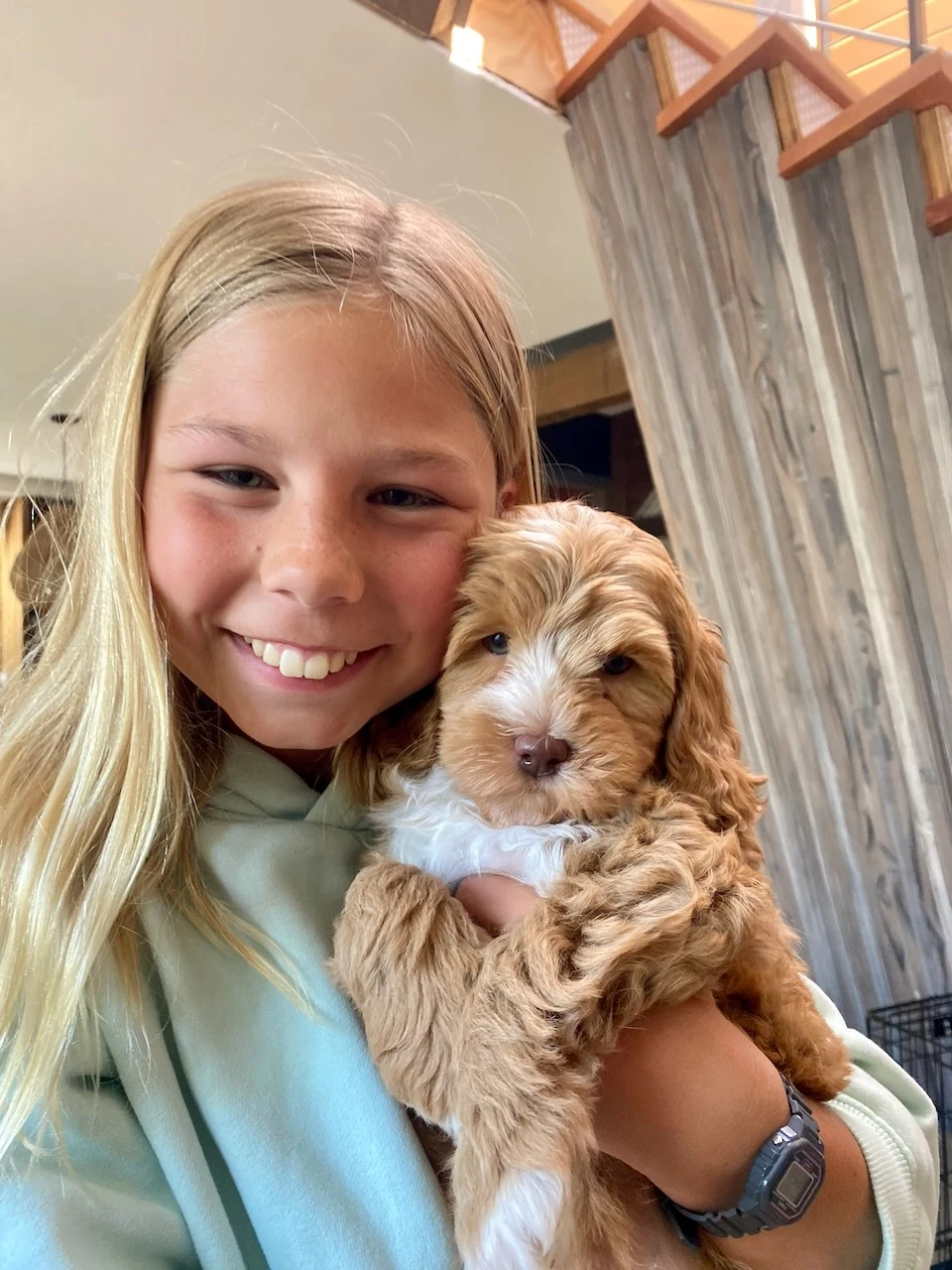 Ivy smiling while holding a small brown-and-white puppy